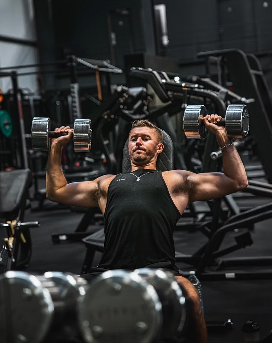 Man lifting dumbbells in a gym.