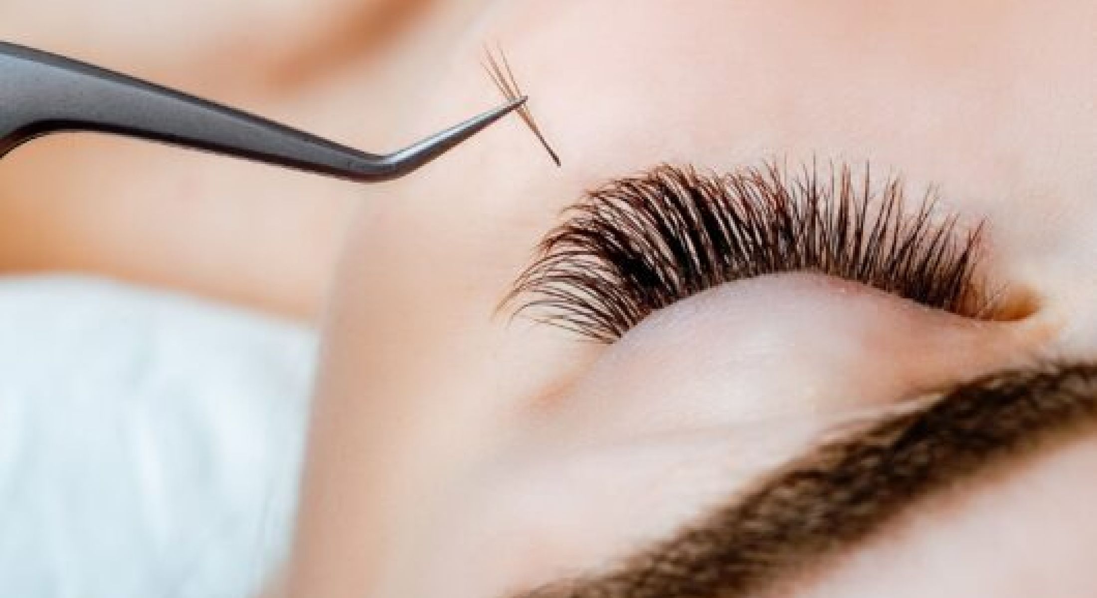 Applying eyelash extensions with tweezers.