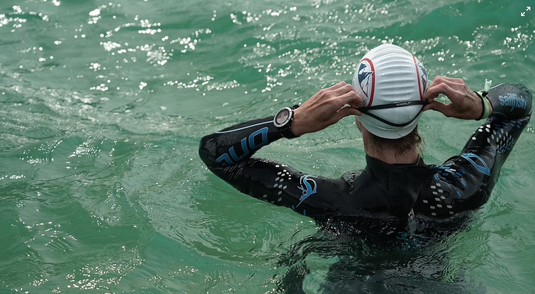 Swimmer adjusting cap in calm water.